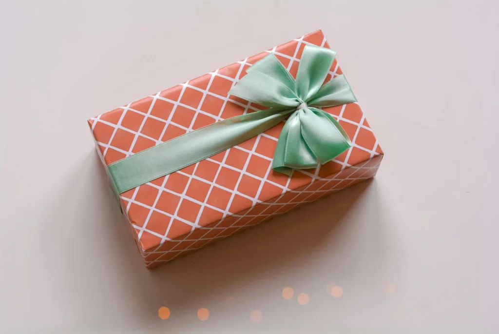 In the picture there is a gift box. The wrapping paper is with square red and white and there is a big light green ribbon.